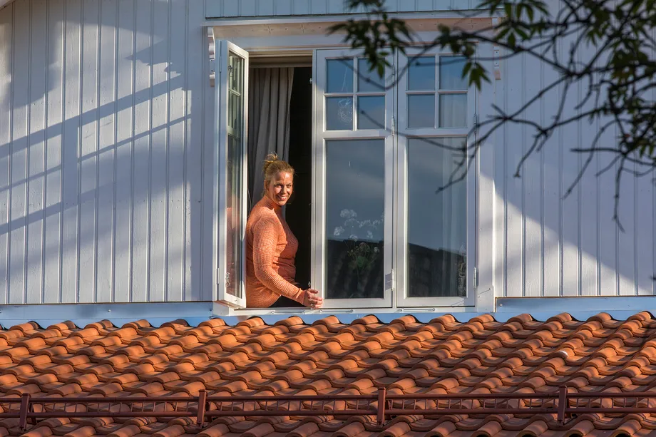 Homeowner who sits in a window and looks out over a new roof of the type Monier Hollander-V from BMI Norway
